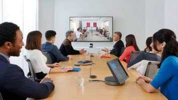 conference room with people around a table participating in a video call